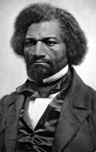 Portrait of Frederick Douglass, full black hair and well trimmed beard, stern gaze.
