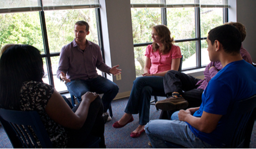 A group of people arranged in a circle having a conversation is shown.