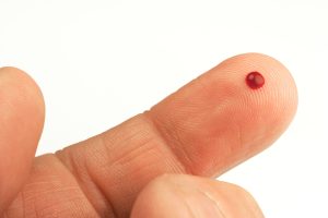 small drop of blood on the tip of a finger