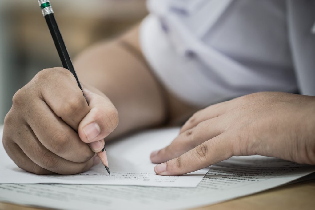 Student taking an exam, writing answers in pencil.