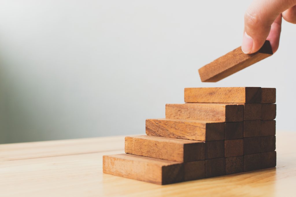 Hand arranging wood blocks as steps.