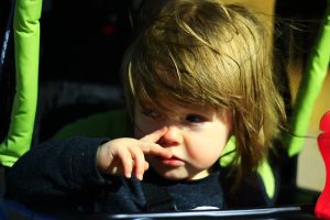 Photograph of a child touching their nose.