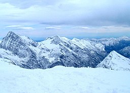 Snow covered mountains with a clouded sky.