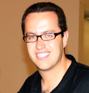 Jared Fogle smiles into the camera with his blue eyes and black-framed glasses.