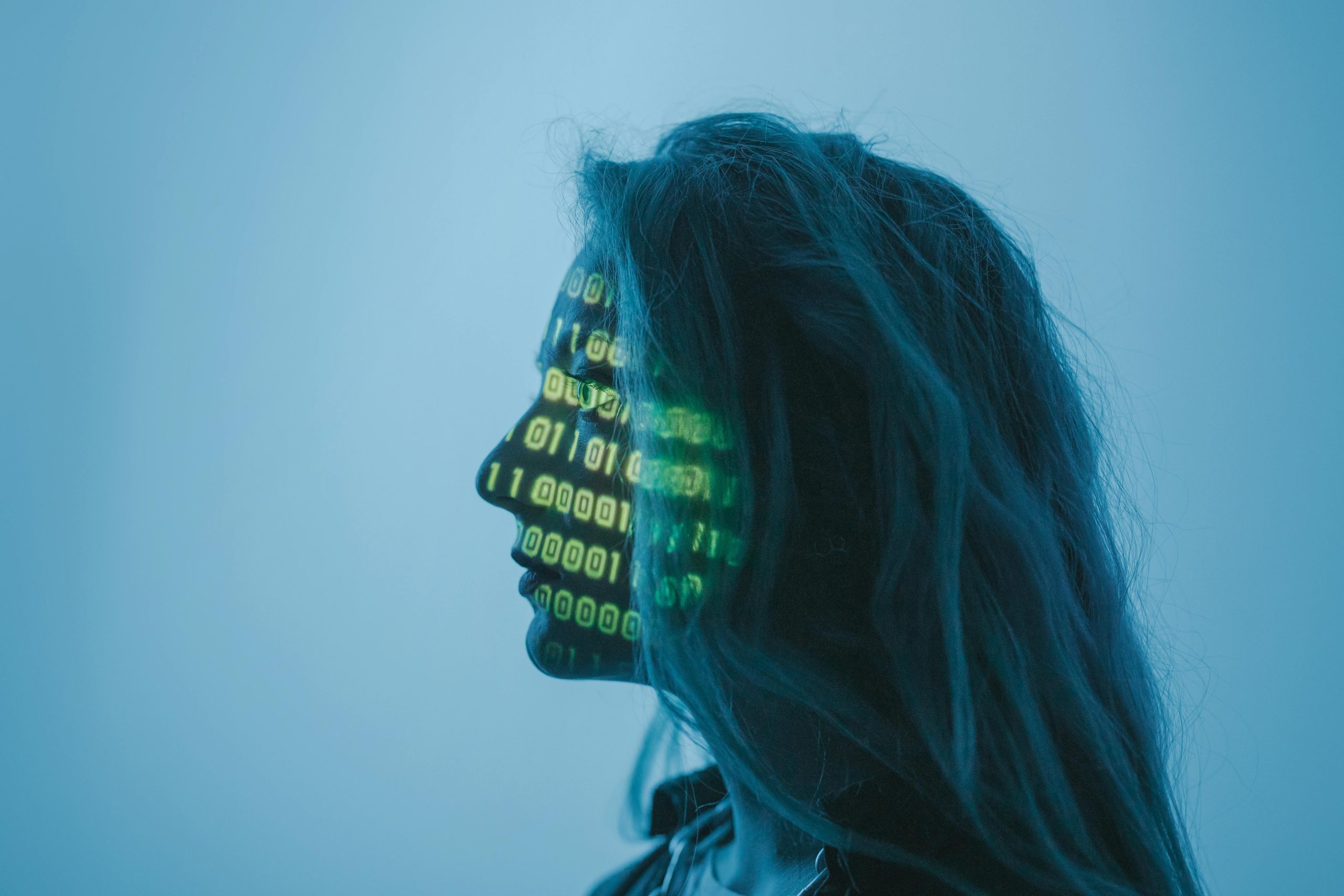 A profile of a women with bright green computer code flashes across her face.