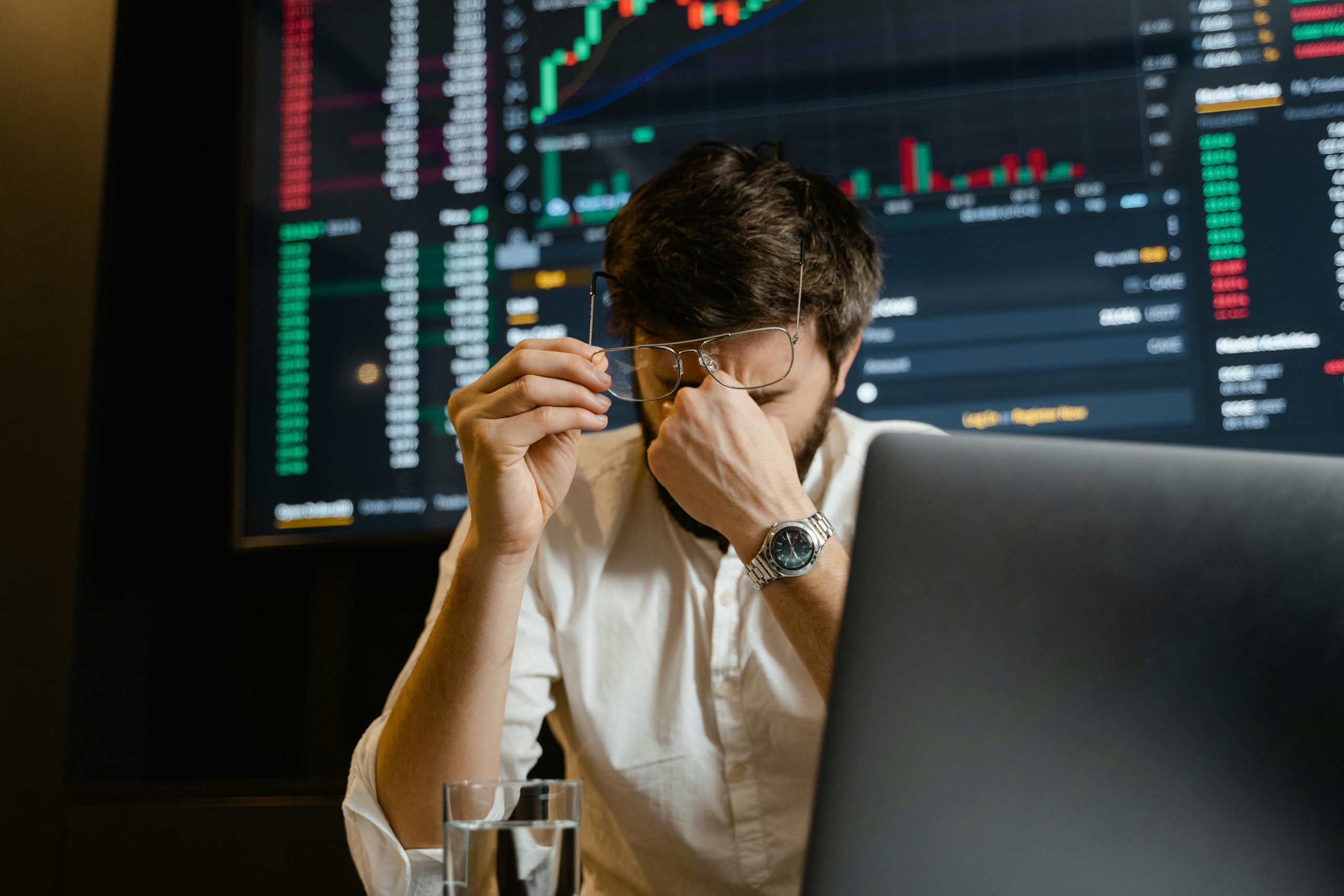 A disgruntled man with his hand on his face sits in front of his computer,