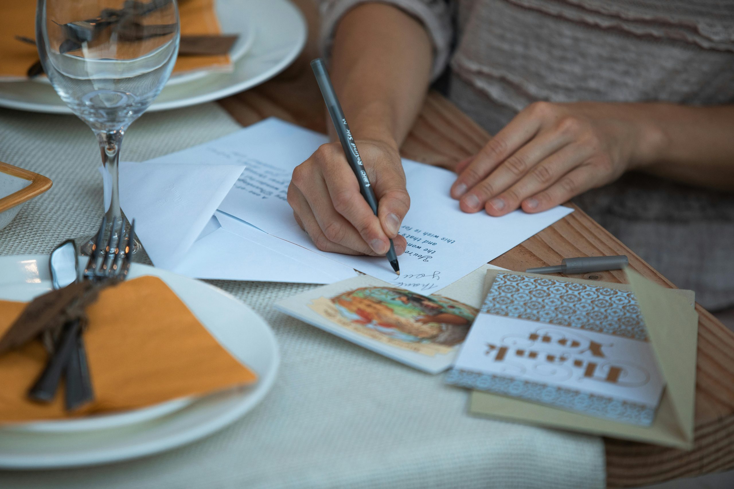 A pair of hands writing a thank you card.