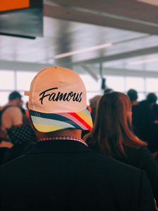 A man, seen from behind, wearing a hat backwards that says "Famous"