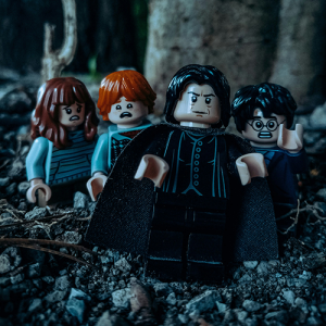 Lego figures of Snape, Harry Potter, Ron Weasley, and Hermione Granger in a dark forest, looking scared