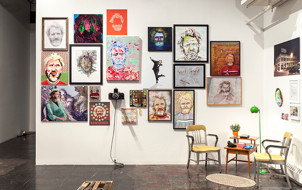 A gallery wall displays a couple dozen portraits of the same man in varying styles and media.