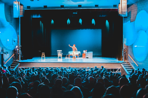 A stage with a performer acting in front of an audience