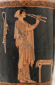 Image of a painted Greek pottery dating back to about 480 BCE depicting a woman laying the aulos.