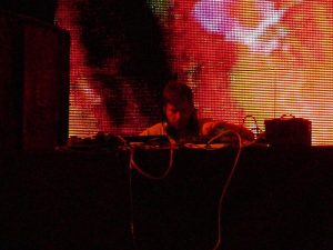 Person using audio equipment in front of a colorful LED screen displaying abstract patterns.
