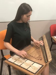 A person playing a qanun, a stringed musical instrument, while seated.