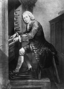 A man in 18th-century clothing playing a pipe organ.