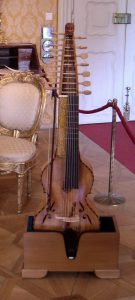 A stringed musical instrument with multiple tuning pegs, displayed on a stand.