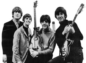 Four men stand together in a black and white photo, smiling towards the camera.
