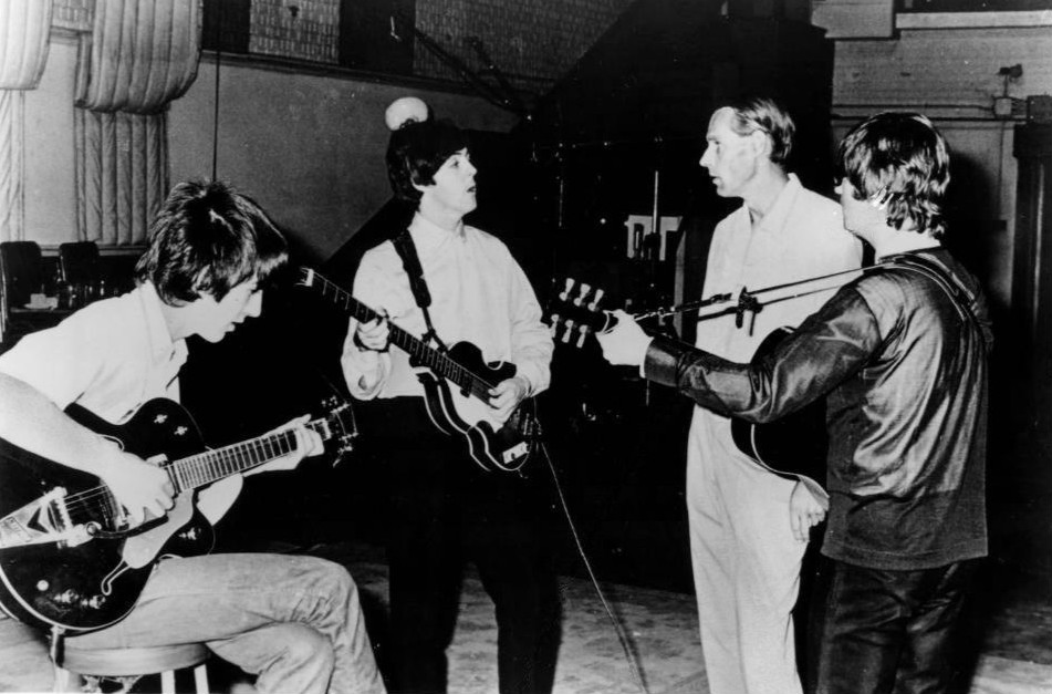 Four people in a recording studio with guitars.