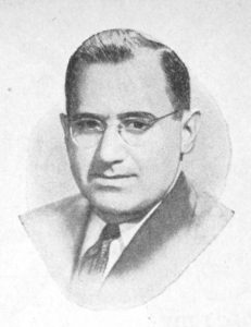 Black and white portrait of a man in a suit and glasses