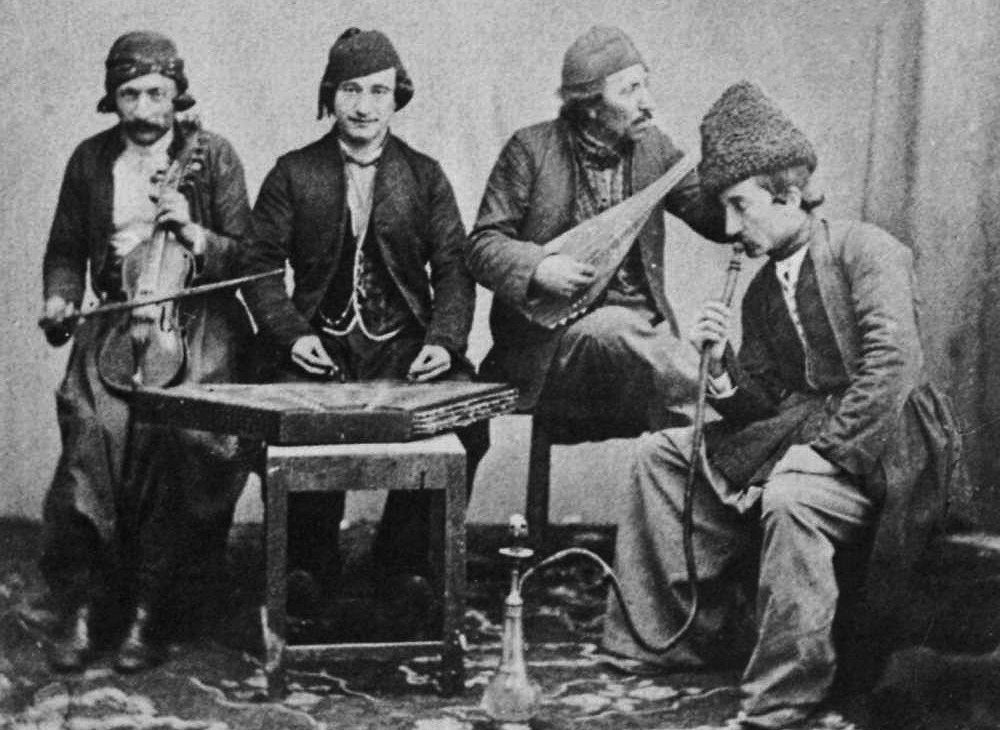 Four men in traditional attire with musical instruments.