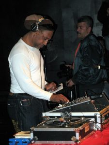 DJ operating a mixing console with turntables.