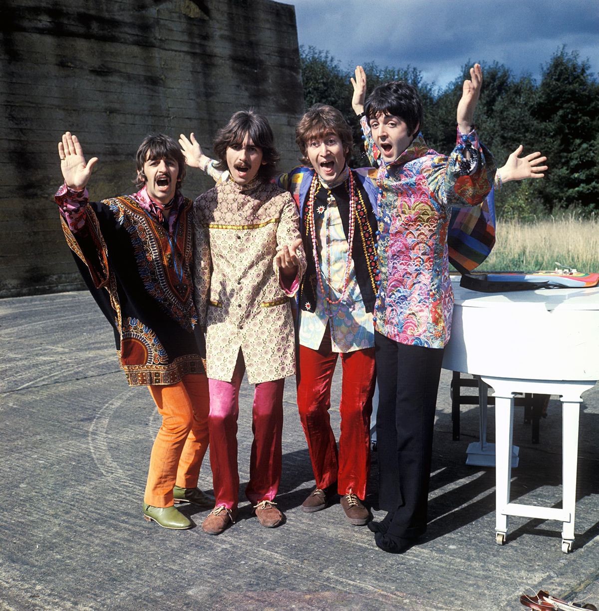 Four men in colorful 1960s attire standing outdoors.