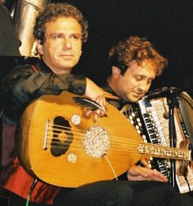 Two musicians performing with an oud and an accordion on stage.
