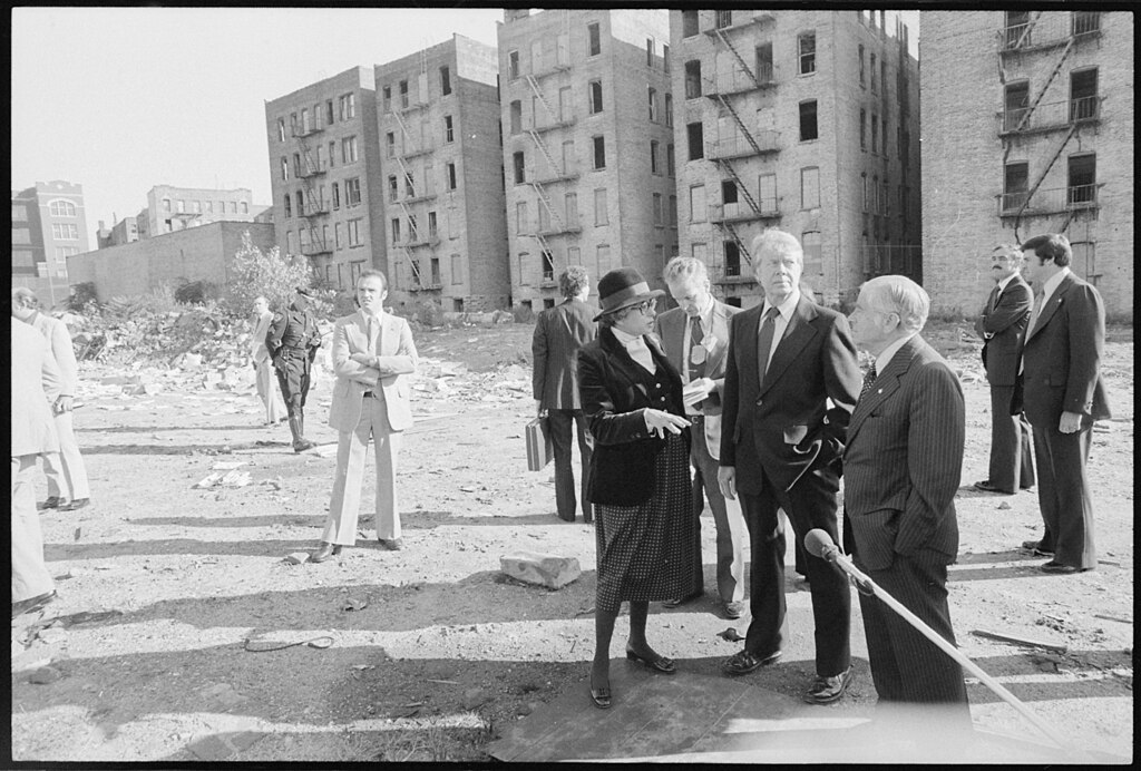 Group of people in an urban area with dilapidated buildings in the background.