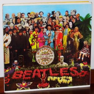Album cover with a crowd of various figures and the word "BEATLES" spelled out in flowers in the foreground.