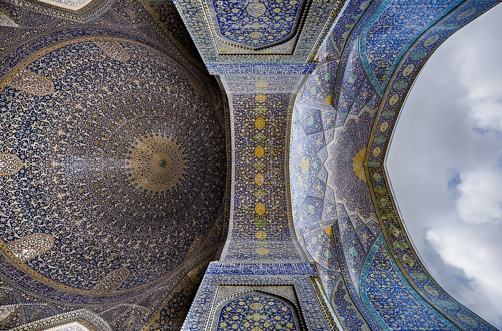 Ornately decorated mosque ceiling and archway with blue and gold geometric patterns.