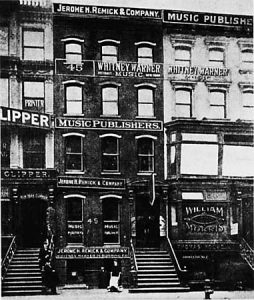 Historical photograph of music publisher buildings with signage, including "Jerome H. Remick & Company" and "Whitney Warner."