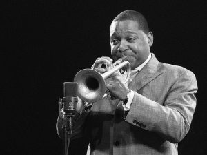 A person in a suit playing a trumpet near a microphone.